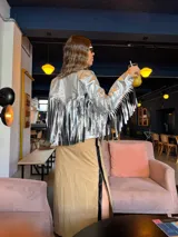 Campera plateada de cuero sintético con flecos en la espalda y mangas.