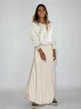 Pollera larga color crudo, de corte recto y confeccionada en satén.
