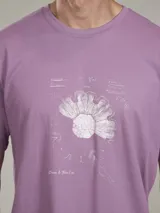 Remera de algodón color celeste, con cuello redondo y manga corta. Presenta un estampado frontal de un diseño botánico en tonos azules y texto.
