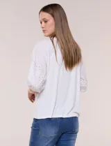 Blusa Liv Los Angeles de color blanco, confeccionada con torso de modal y mangas tres cuartos con detalles de bordado calado. Presenta cuello redondo con apertura central y cierre frontal de botones.