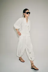 Camisa blanca de algodón con escote en pico, mangas por debajo del codo y detalles de bordados y encaje a tono en el pecho y las mangas.