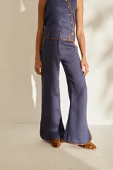 Pantalón azul marino de corte wide leg con detalles en tono marrón tostado en la cintura, bolsillos y bordes laterales, cuenta con trabillas para cinturón y cierre frontal.