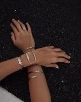 Pulsera tipo esclava abierta con diseño rústico y acabado irregular, fabricada en bronce y alpaca.