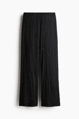 Pantalón de corte holgado confeccionado en tejido con textura efecto encaje, de tiro bajo y piernas extralargas, con cintura elástica y cordón ajustable.