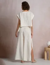 Blusa corta de lino marca Elan, de corte crop con silueta holgada, hombros caídos, escote amplio a la base y aberturas laterales ajustables con lazos para anudar.
