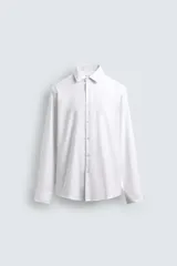 Camisa blanca de manga larga con cuello italiano y puños abotonados, confeccionada en tejido de algodón.