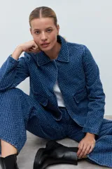 Chaqueta de jean con textura tipo desflecado, color azul medio, con cuello camisero, cierre frontal con botones y bolsillos delanteros con solapa.