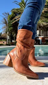 Bota alta de cuero color marrón, con efecto fruncido en la caña y taco ancho cuadrado.