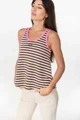 Musculosa de corte holgado con diseño a rayas horizontales en tonos marrón y crudo. Presenta ribetes en color fucsia en el cuello redondo y en las sisas, además de un pequeño bordado decorativo en el centro del pecho.