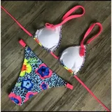 Conjunto de bikini United Uy modelo Mili, con estampado colorido de flores sobre fondo celeste con patrón de leopardo. El corpiño es de diseño triangular con tirantes fucsias y la bombacha es de corte tanga con detalles ajustables en los laterales.
