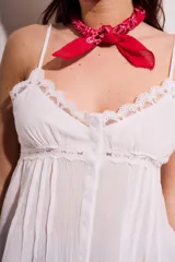 Blusa negra de algodón con tirantes finos, escote en V decorado con encaje y cierre frontal con botones. Presenta un corte holgado con detalles de encaje en el borde inferior.