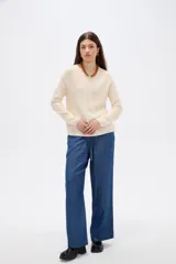 Sweater de tejido de punto fino en color blanco, con cuello redondo a la base y mangas largas de corte holgado.