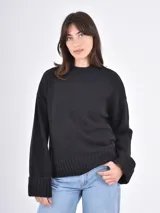 Buzo de tejido de punto color negro, con cuello redondo, mangas largas con puños anchos y ruedo acanalado.