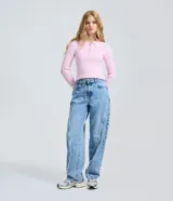Pantalón baggy en denim de algodón con cintura media y lavado claro. Presenta costuras verticales deshilachadas al frente, bolsillos funcionales y corte amplio y recto.