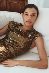 Vestido midi dorado cubierto de lentejuelas, con cuello redondo, mangas cortas y espalda abierta con cordones para ajustar.
