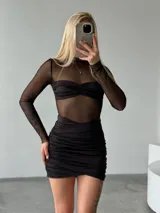 Vestido corto negro confeccionado en tela transparente con efecto segunda piel y detalles drapeados en el corpiño y la minifalda ajustada.