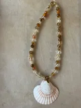 Collar largo de cuentas de piedras semipreciosas en tonos tierra, con dijes de conchas marinas.