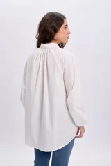 Camisa blanca de manga larga abullonada estilo globo, con cuello camisero, cierre frontal parcial de botones y diseño holgado.