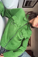 Chaqueta corta de tejido efecto ante en color verde vibrante, con cuello solapa, cierre frontal de cremallera y mangas largas. Presenta dos bolsillos frontales con solapa decorados con arandelas metálicas en el pecho.