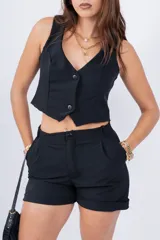 Short de vestir negro con cintura alta, pinzas delanteras y ruedo doblado.