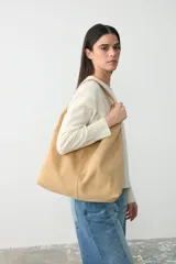 Cartera tipo tote de tamaño mediano, confeccionada en cuero suave de color beige. Presenta un diseño minimalista y amplio con bolsillo interior.