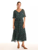 Vestido midi de gasa estampada en tonos verdes y marrones, con escote en V cruzado en la parte delantera y escote redondo elastizado en la espalda. Presenta cintura elastizada con lazo fino para anudar, mangas cortas evasé con volumen y falda con volados escalonados. Incluye forro interno a tono.