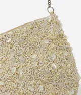 Cartera bandolera pequeña de forma rectangular, completamente cubierta de lentejuelas y cuentas brillantes en tono crema. Cuenta con cierre superior y una correa de cadena metálica plateada.