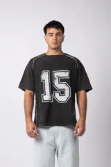 Remera de algodón con efecto de lavado gastado, color negro, con estampa frontal del número 15 en color blanco y detalles de costuras blancas en los hombros y laterales.