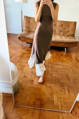 Vestido largo de cuello perkins y diseño sin mangas, confeccionado en tejido de punto color marrón. Presenta un bajo con corte evasé y detalle de encaje en color crudo a contraste. Cierre posterior con cremallera oculta.