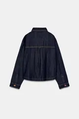 Cazadora de denim en color azul oscuro con costuras en contraste, cuello solapa, manga larga y cierre frontal con botones metálicos. Presenta dos bolsillos de plastrón en el delantero.
