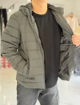 Campera puffer azul marino con capucha ajustable, cierre frontal y bolsillos laterales con cierre a presión. Cuenta con parche redondo con la inscripción "TURK" en el pecho.