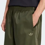 Bermuda Adidas Twill color verde militar, de corte holgado y largo por debajo de la rodilla. Cuenta con cintura elástica, bolsillos laterales y las clásicas tres tiras de la marca en los laterales.