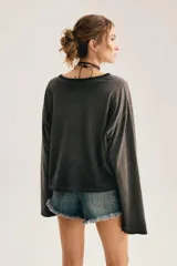 Remera de manga larga gris oscuro con efecto lavado gastado, corte oversize y cuello redondo amplio. Cuenta con estampado tipográfico manuscrito en el pecho.