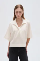 Blusa de lino color natural, con cuello polo y escote en V, de mangas cortas holgadas y corte recto.
