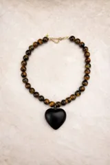 Collar de cuentas esféricas de piedra ojo de tigre con dije central en forma de corazón de madera pulida en tono rojizo.