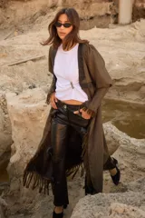 Tapado de silueta recta con estampado de cuadros, escote en V profundo y cierre frontal con un único botón. Presenta mangas largas con leve volumen, tajos laterales y terminaciones con flecos en el ruedo.