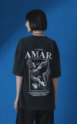 Remera de manga corta con cuello redondo y calce oversize, confeccionada en algodón premium con efecto de lavado nevado. Presenta una estampa gráfica en la espalda con diseño de palomas y texto alusivo.