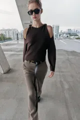 Jersey de punto color marrón oscuro, con cuello redondo y manga larga. Presenta un diseño con aberturas y nudos decorativos en los hombros.