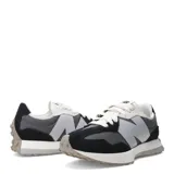 Championes urbanos New Balance modelo 327, con diseño retro que combina paneles de gamuza negra y malla gris. Presenta el logo 'N' sobredimensionado en color gris claro en el lateral, cordones blancos y una suela de goma con relieve que se extiende hacia el talón.