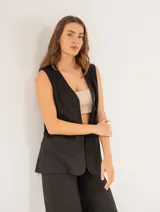 Pantalón negro de lino, tiro alto, corte palazo, con elástico en la pretina trasera, cierre delantero y broche interno. Tiene bolsillos laterales, dobladillo invisible y tajos a los costados.