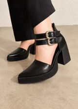 Zapatos de tacón alto en color negro, combinando texturas de napa y croco, con diseño de punta fina, plataforma delantera, tacón ancho y doble tira con hebillas metálicas doradas en el tobillo.