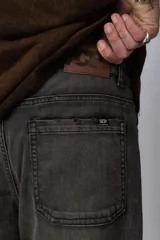 Pantalón de jean con lavado oxidado, de corte mom y tiro medio. Presenta costuras verticales visibles y detalles de terminaciones deshilachadas en las piernas.