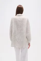 Camisa de corte holgado con cuello clásico y cierre frontal de botones. Presenta mangas largas con puños y un diseño de rayas verticales finas en tonos neutros.