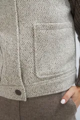 Campera de lana fina color crema, con cuerpo estructurado y mangas de tejido de punto acanalado. Presenta cuello alto, cierre frontal con botones y bolsillos laterales con doble abertura.