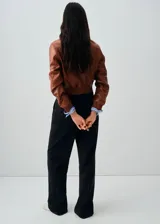Chaqueta de cuero ovino color marrón, con diseño corto, cuello camisero, cierre frontal con botones y puños elásticos.