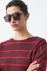 Sweater de tejido de punto con diseño de rayas horizontales en tonos bordó y rojo. Presenta cuello redondo, mangas largas con hombros caídos y terminaciones acanaladas en puños, cuello y ruedo.
