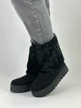 Botas negras de caña media con plataforma y detalle de piel sintética en la parte superior.