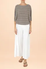 Suéter de punto con acabado metalizado, diseño de rayas horizontales, cuello bote y mangas estilo murciélago con puños ajustados.