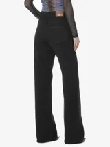 Pantalón denim negro de tiro alto, con pretina con pasacinto, bolsillos delanteros y traseros, y pierna ancha.