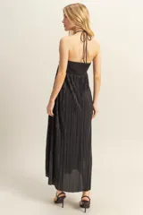 Vestido largo de corte fluido con diseño plisado en toda la prenda. Presenta escote halter con detalle de nudo en el centro del pecho y espalda descubierta.